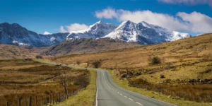 Road stretching up to Snowdonia with snowy mountain tops