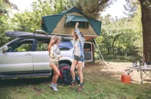 children playing outside in front of a car with a rooftop tent