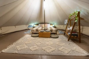interior view of a glamping yurt with a bed, rug, and lighting